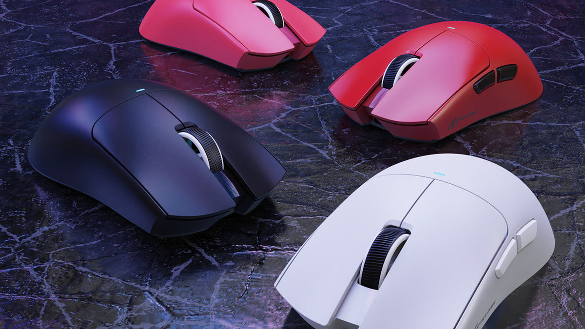 Four Attack Shark gaming mice in different colors (black, white, red, and pink) on a dark marble surface