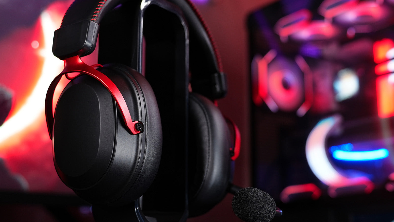 A close-up of a sleek black over-ear gaming headset with striking red metal arms resting on a stand
