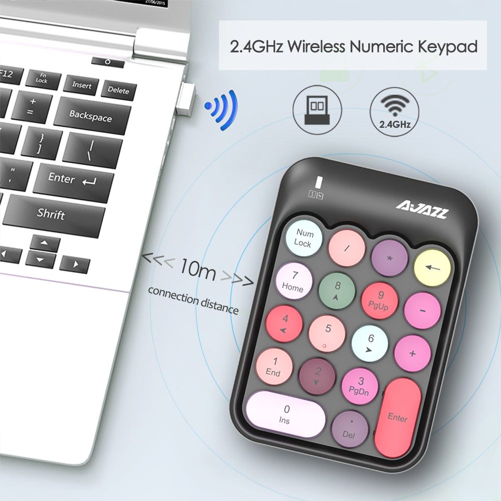 Black wireless numeric keypad with pastel keys beside a laptop, showcasing wireless features.