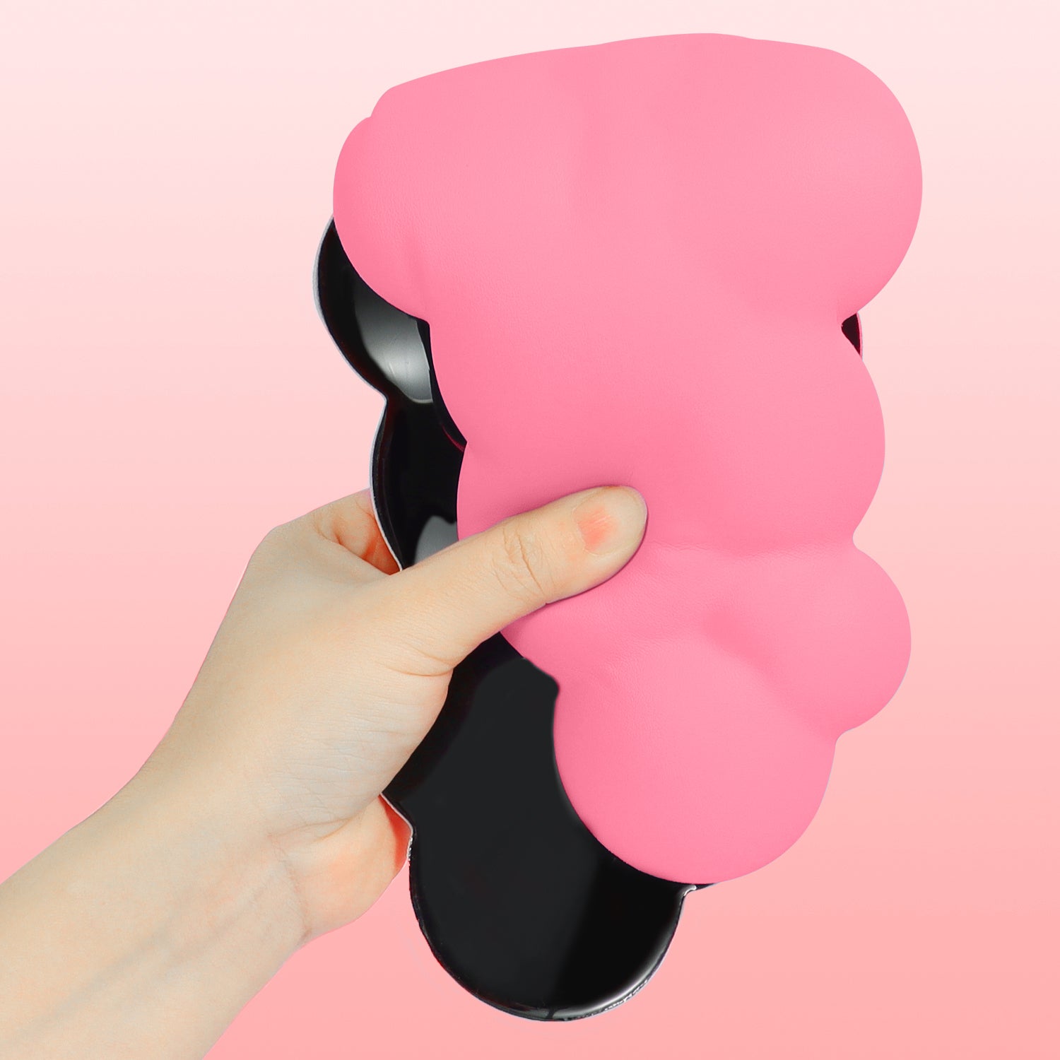 Hand holding pink cloud-shaped ergonomic wrist rest with anti-slip base.