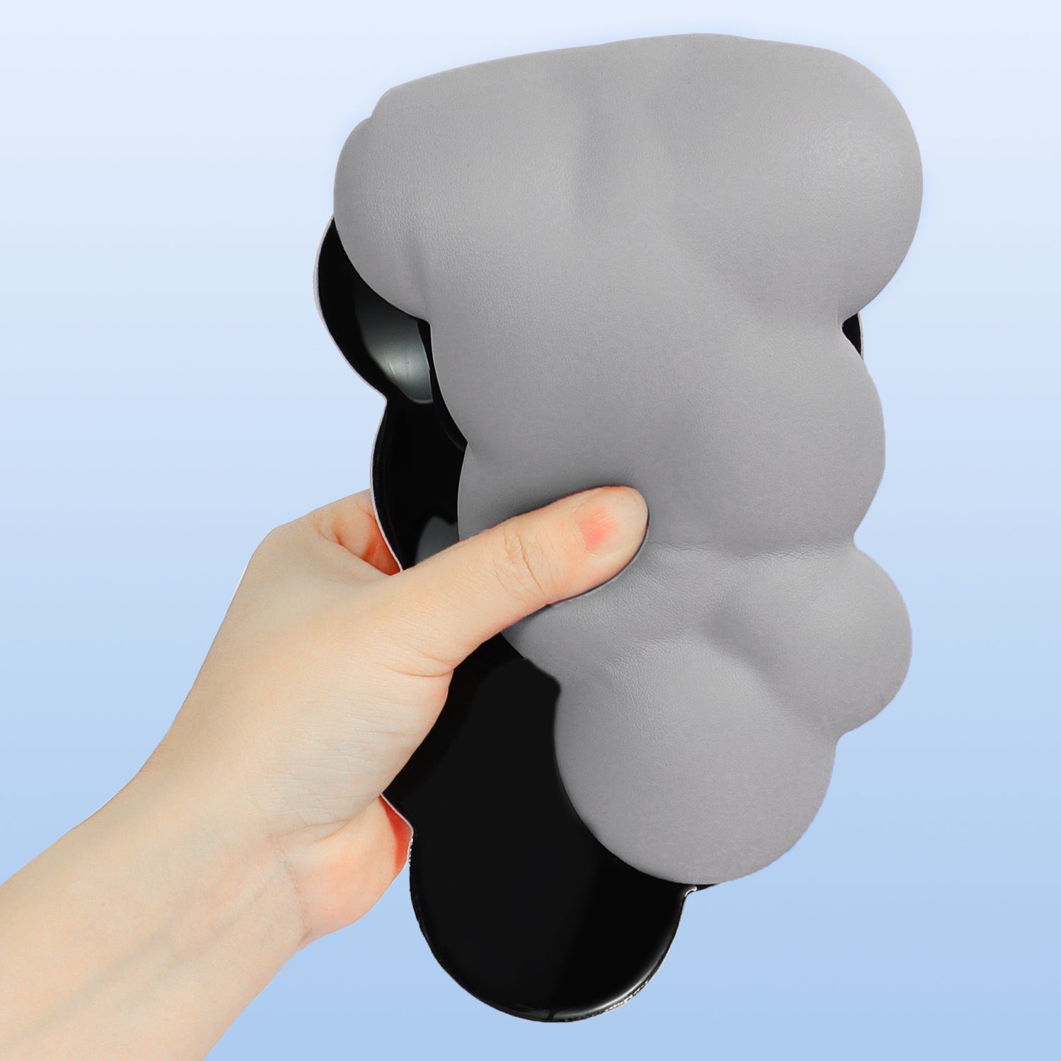 Hand holding gray cloud-shaped ergonomic wrist rest for comfortable gaming and typing.