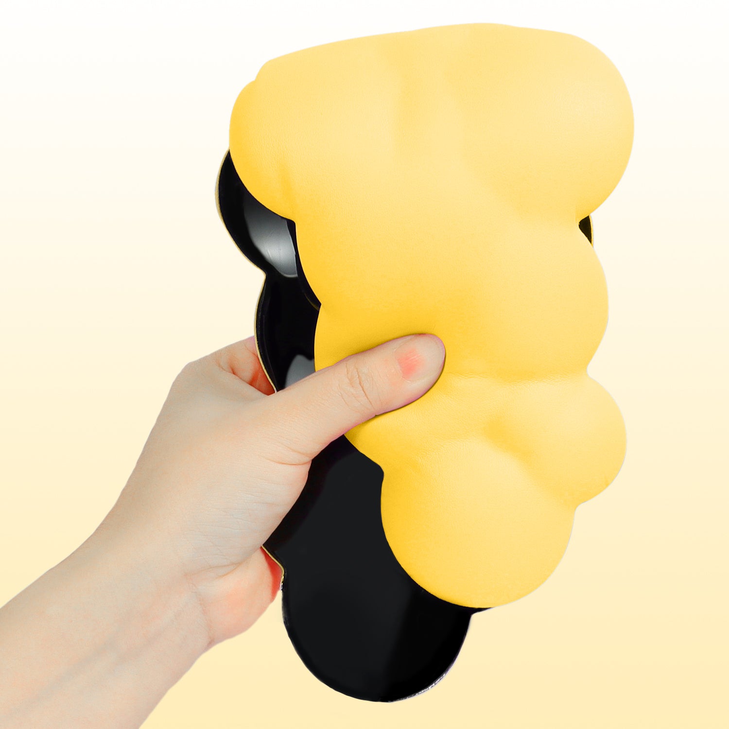 Hand holding yellow cloud-shaped ergonomic wrist rest with anti-slip base.