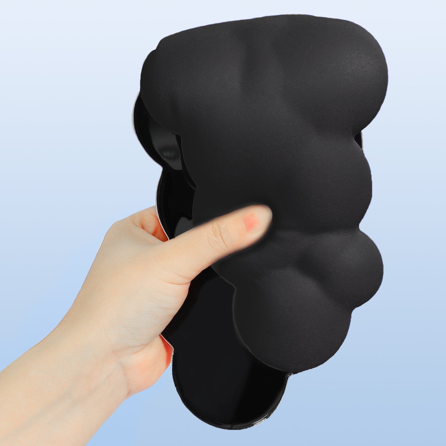 Hand grasping black memory foam cloud-shaped wrist rest.