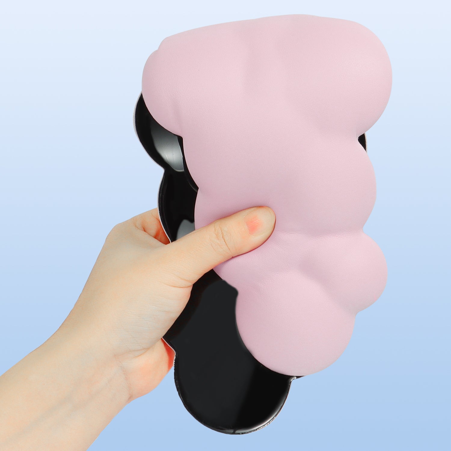 Hand holding a pink cloud-shaped ergonomic wrist rest with anti-slip base.