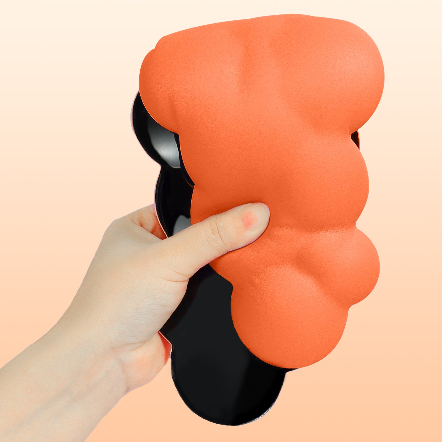 Hand squeezing ergonomic orange cloud-shaped wrist rest for comfort.