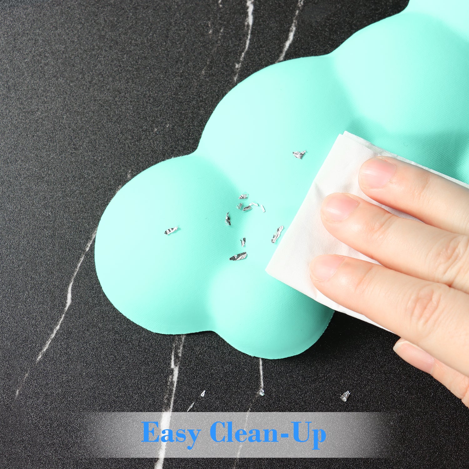 Mint green cloud wrist rest with easy clean-up feature being wiped by a hand.