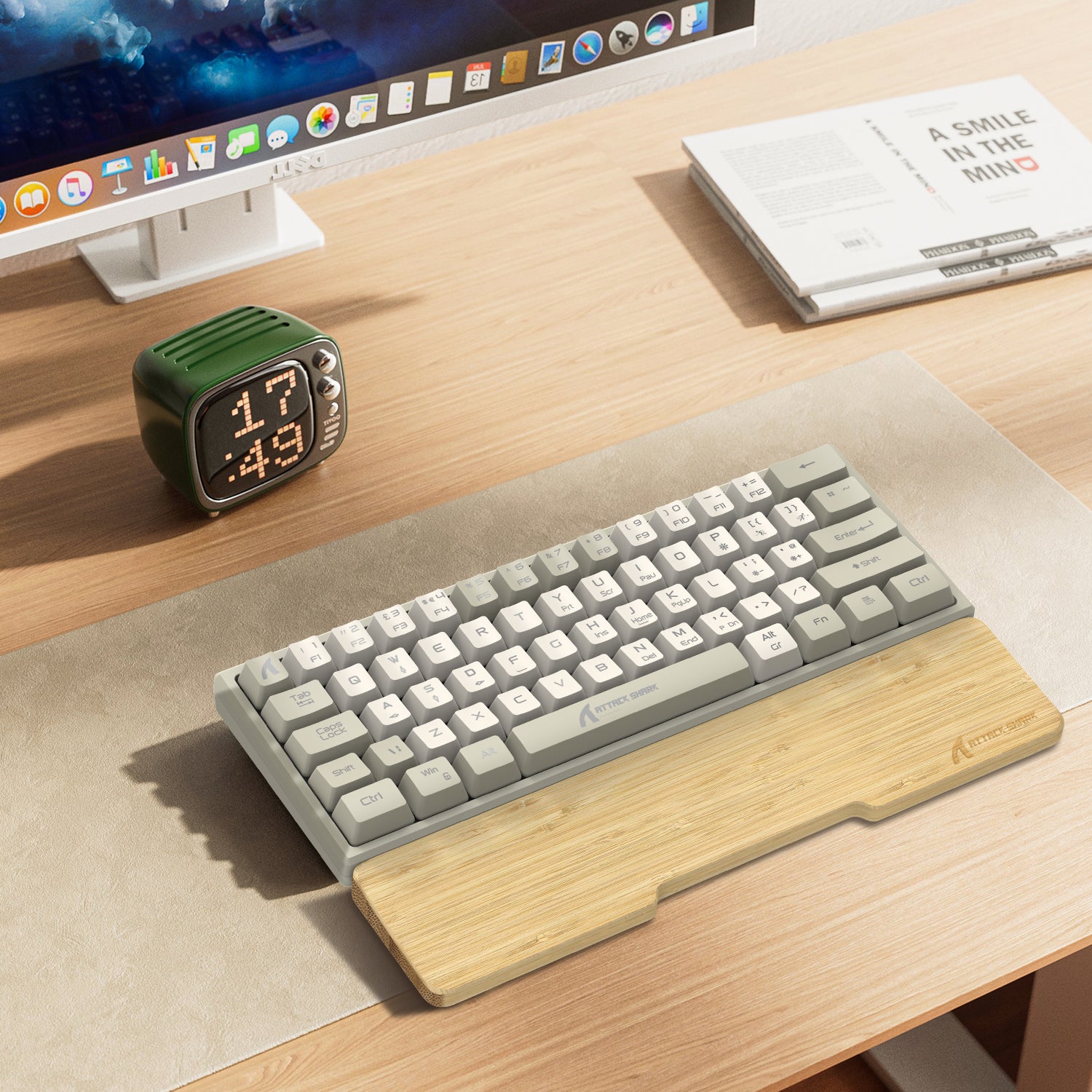 Bamboo wrist rest with compact creamy gray keyboard and green clock on wooden desk.