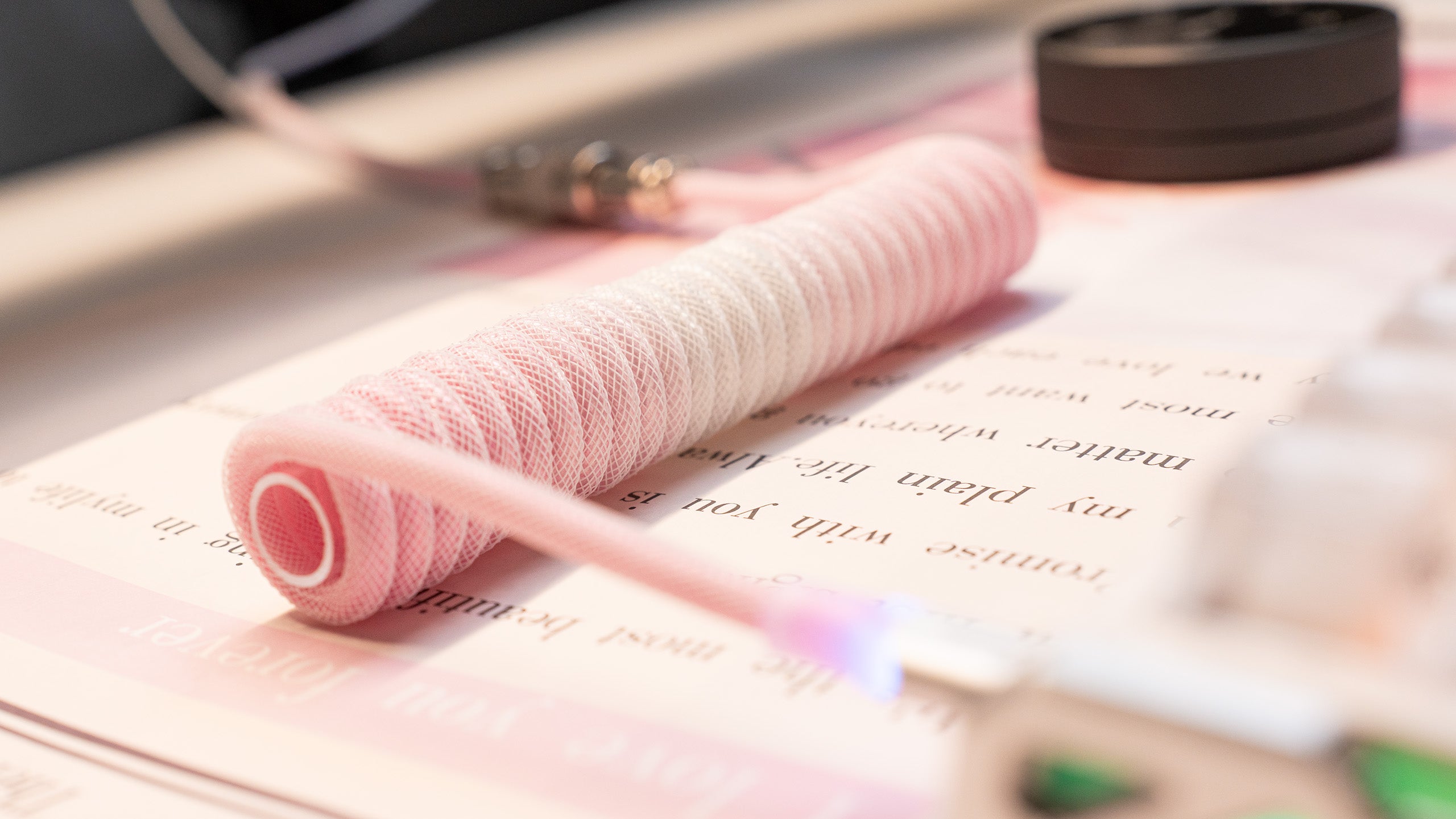 Pink and white coiled USB-C keyboard cable with translucent glow, aviator connector